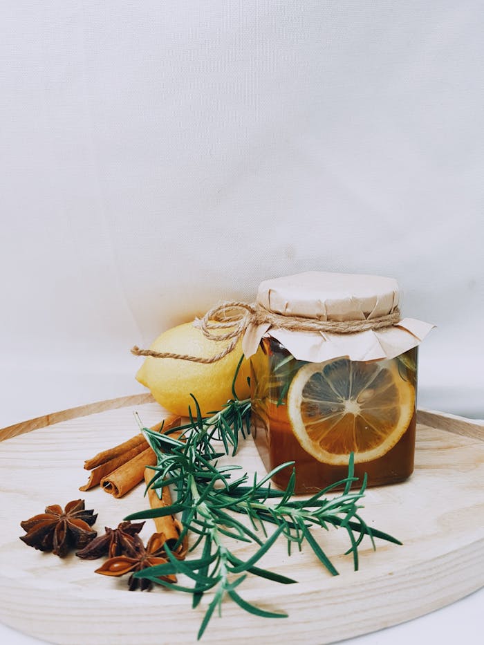 Artistic arrangement of lemon, herbs, and honey jar for DIY herbal tea.